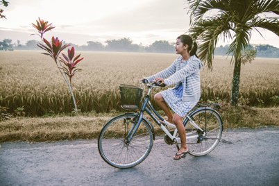 A girl is having a bicycle trip through the rice fields in Bali